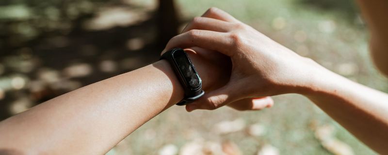 A fitness band on a wrist outdoors, dappled park light behind